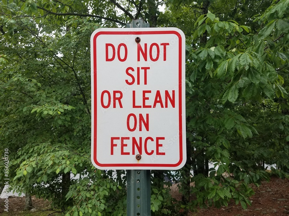 white and red do not sit or lean on fence sign