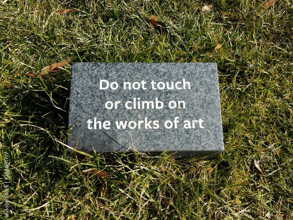 do not touch or climb the works of art sign in grass