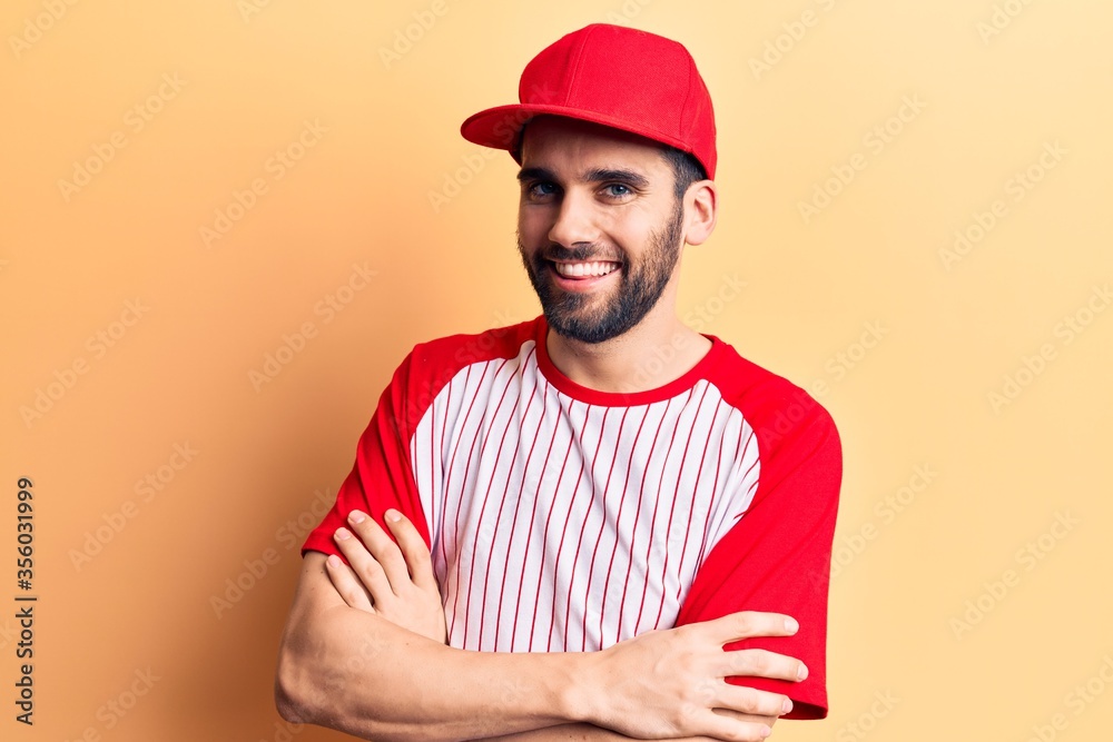 Young handsome man with beard wearing baseball cap and t-shirt happy face smiling with crossed arms looking at the camera. positive person.