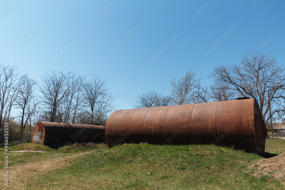 Two old abandoned rusty barrels lie in the open air on the grass Two old abandoned rusty barrels lie in the open air on the grass