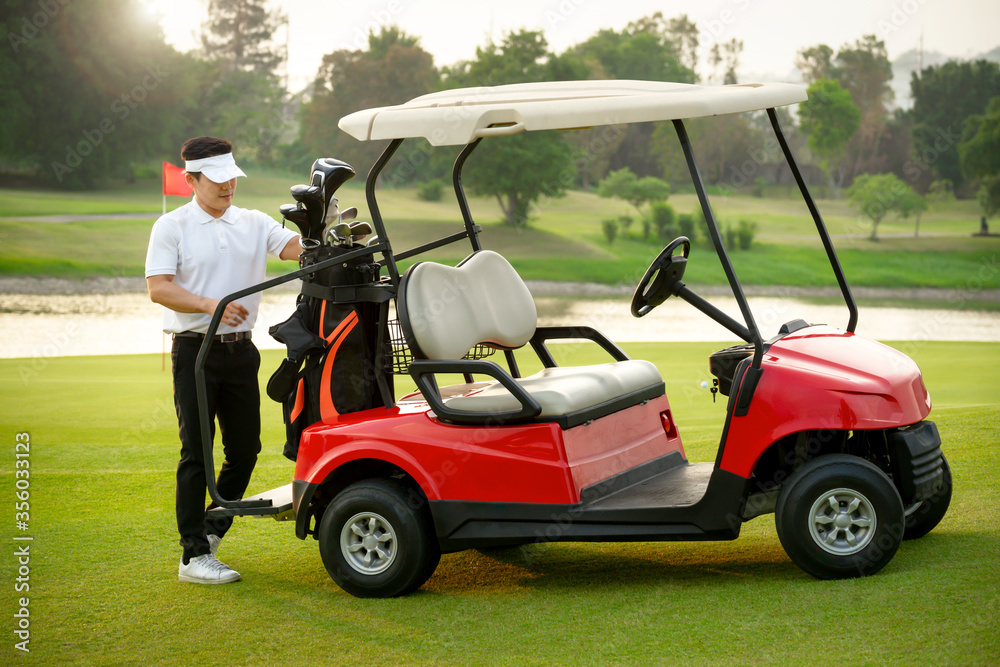 The golfer stands and picks the golf club from the bag at the back of the golf cart.