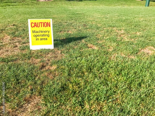 Caution sign sitting on the grass of a public park