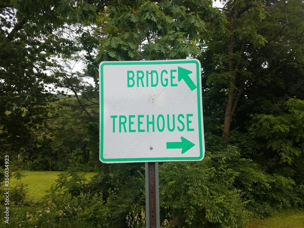 white and green bridge and treehouse sign with arrows