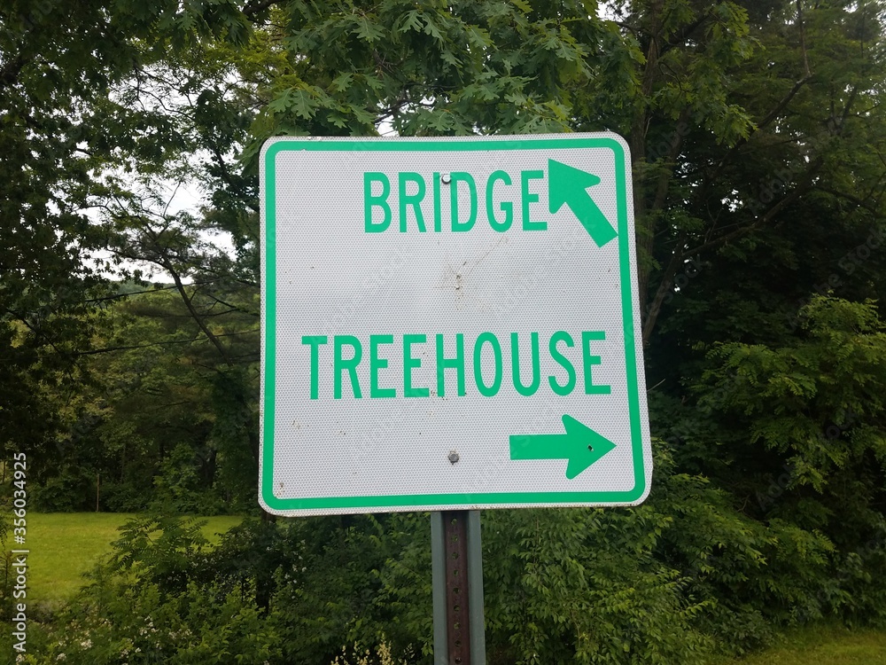 white and green bridge and treehouse sign with arrows