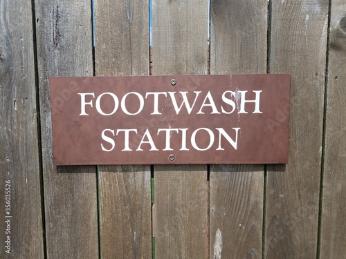 footwash station sign on brown wood fence
