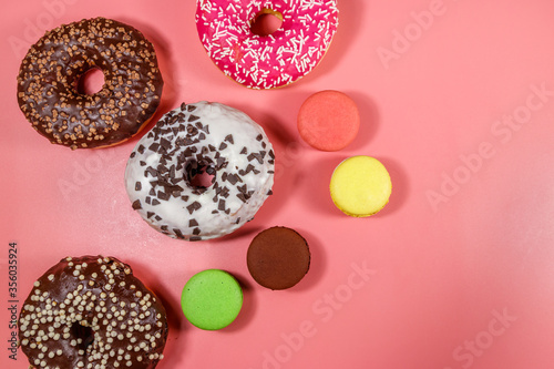 Tasty donuts and macaroons on pink background. Top view