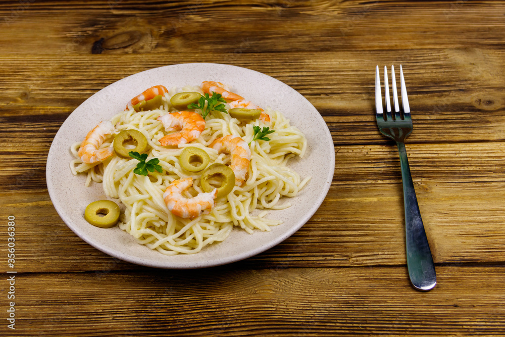 Spaghetti pasta with prawns, green olives and parsley on wooden table Spaghetti pasta with prawns, green olives and parsley on wooden table