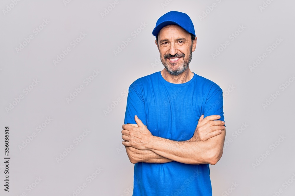 Middle age handsome deliveryman wearing cap standing over isolated white background happy face smiling with crossed arms looking at the camera. Positive person.
