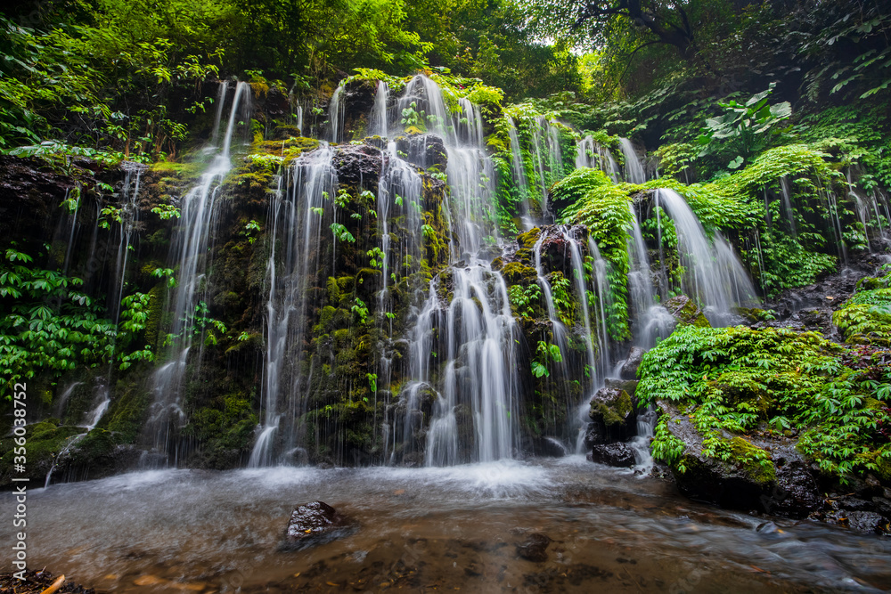 Waterfall landscape. Beautiful hidden waterfall in tropical rainforest. Nature background. Slow shutter speed, motion photography. Banyu Wana Amertha waterfall, Bali, Indonesia Waterfall landscape. Beautiful hidden waterfall in tropical rainforest. Nature background. Slow shutter speed, motion photography. Banyu Wana Amertha waterfall, Bali, Indonesia