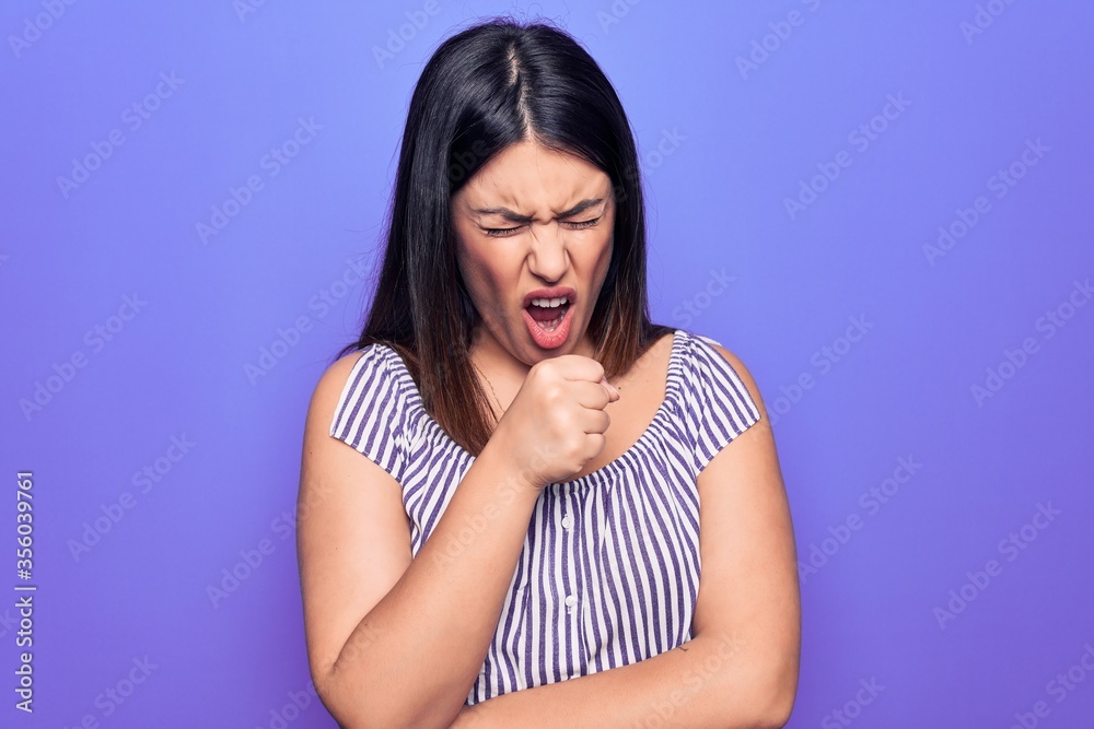 Young beautiful brunette woman wearing casual striped t-shirt standing over purple background feeling unwell and coughing as symptom for cold or bronchitis. Health care concept. Young beautiful brunette woman wearing casual striped t-shirt standing over purple background feeling unwell and coughing as symptom for cold or bronchitis. Health care concept.