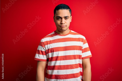 Wallpaper Mural Young brazilian man wearing casual striped t-shirt standing over isolated red background depressed and worry for distress, crying angry and afraid. Sad expression. Torontodigital.ca