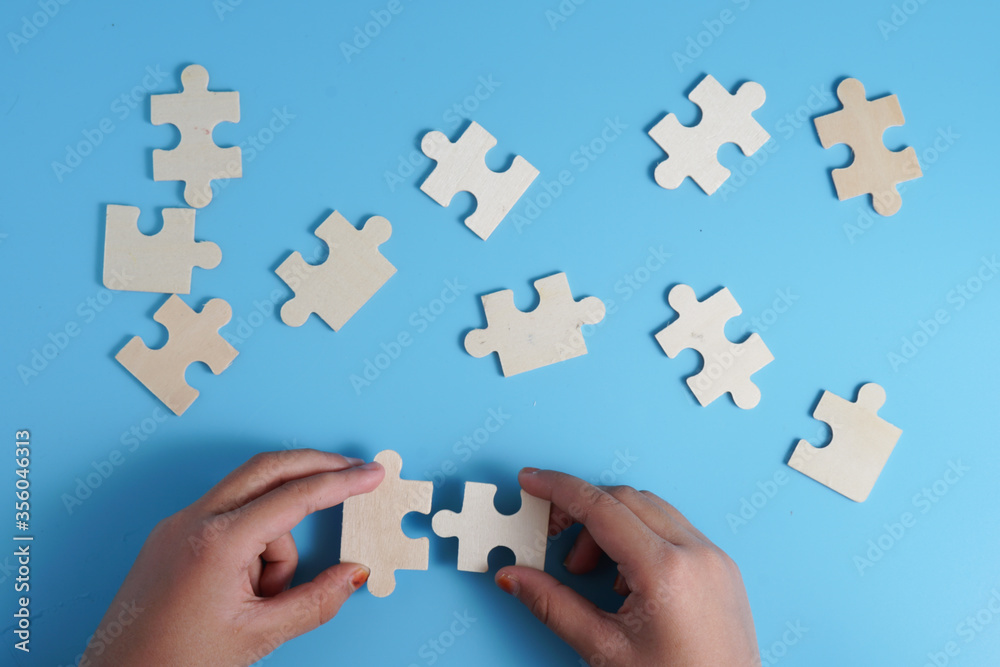 Child's hands holding two puzzle pieces on blue background as a symbol of autism awareness.
