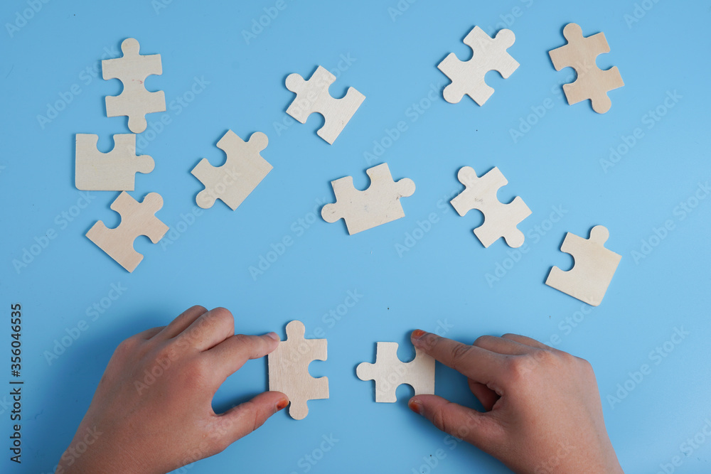 Child's hands holding two puzzle pieces on blue background as a symbol of autism awareness.
Child's hands holding two puzzle pieces on blue background as a symbol of autism awareness.