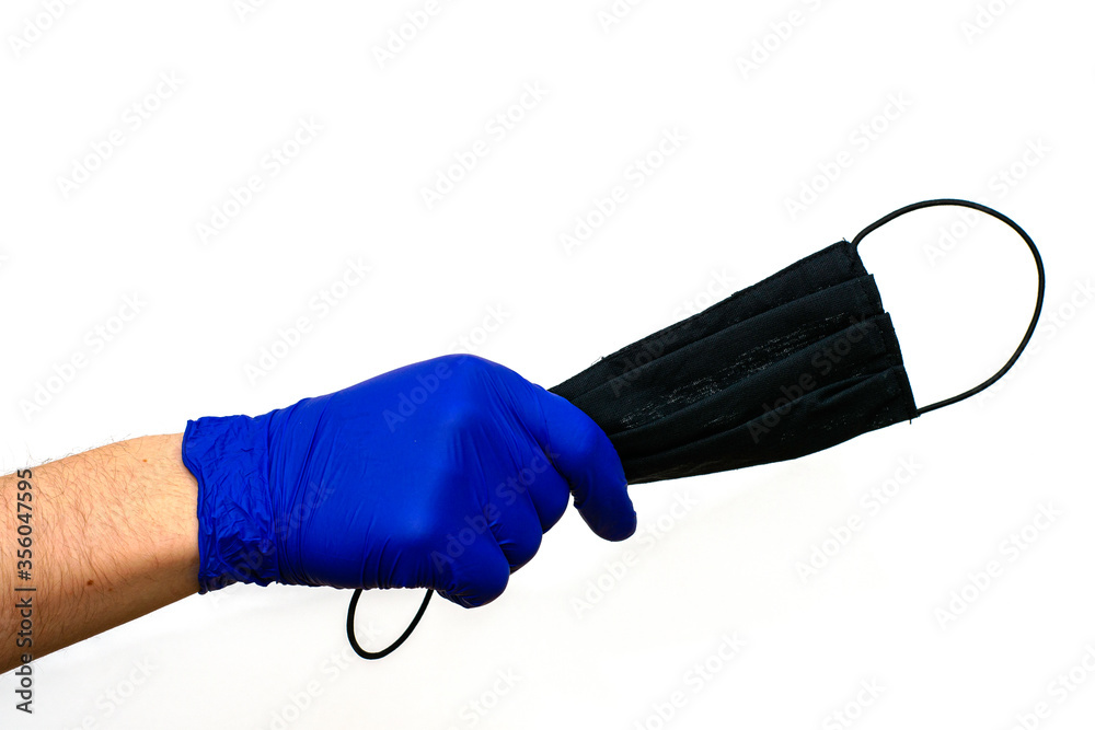 hand in a blue medical glove holds a black hygiene mask on the white background hand in a blue medical glove holds a black hygiene mask on the white background