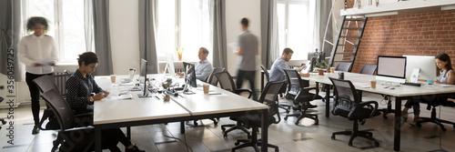 Group of multi ethnic corporate employees working in co-working open space walking in motion, sit at shared desks. Busy workday, office rush concept. Horizontal photo banner for website header design