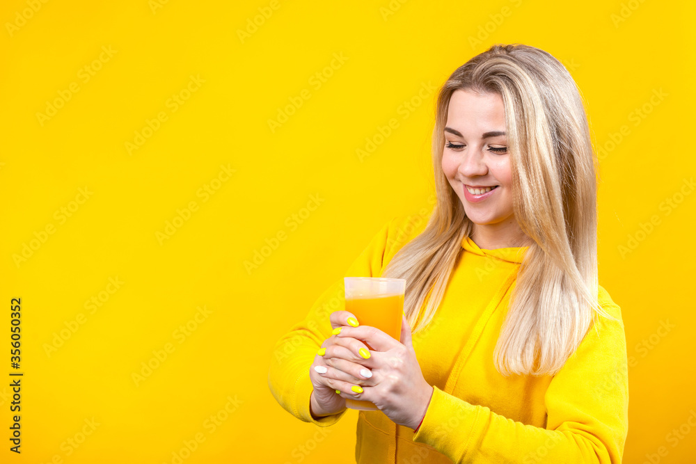 Happy beautiful young blonde woman in yellow casual sporty clothes holding orange juice glass, Happy beautiful young blonde woman in yellow casual sporty clothes holding orange juice glass,