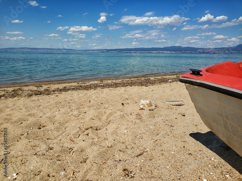 Front of a boat on a stunning sandy beach in the area of Thessaloniki Greece. Blue summer sky with clouds.