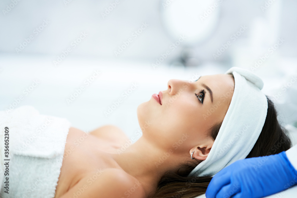 Beautiful young woman getting face treatment at beauty salon.