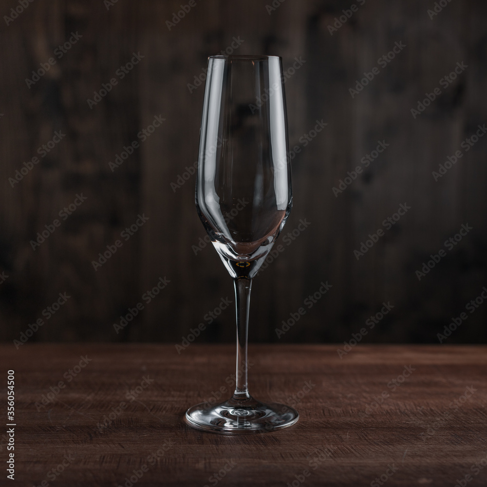Empty champagne glass on wooden table against dark background in bar. Catering Concept Empty champagne glass on wooden table against dark background in bar. Catering Concept