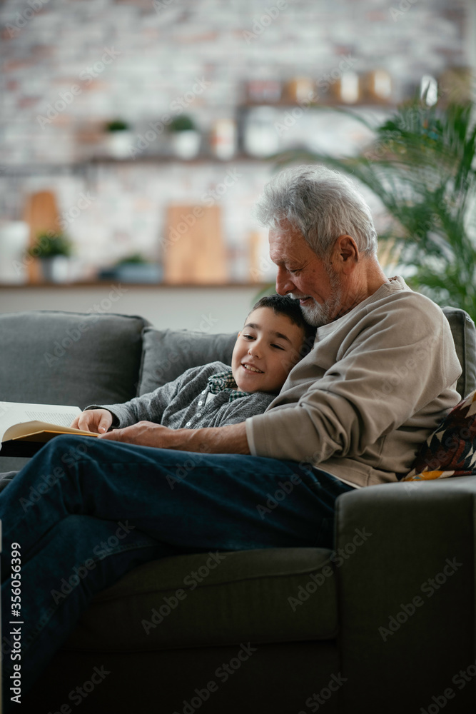 Grandfather and grandson reading a book. Grandpa and grandson enjoying at home.	