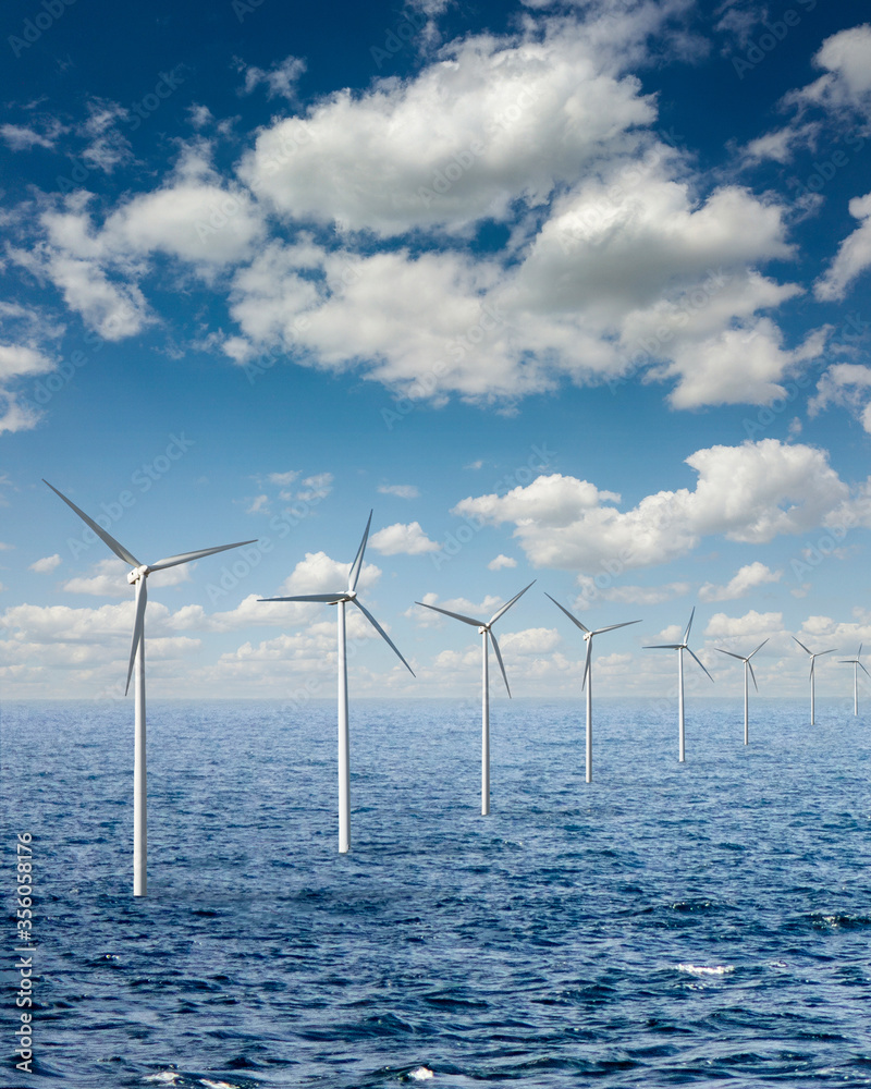 Row from wind turbines in an open sea water on a background of cloudy sky.