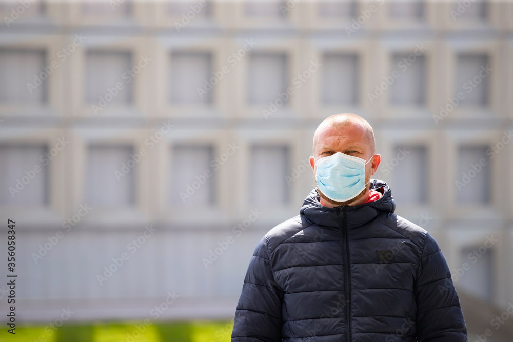 Portrait of brunette man in a medical surgical mask in the city. Portrait of brunette man in a medical surgical mask in the city.