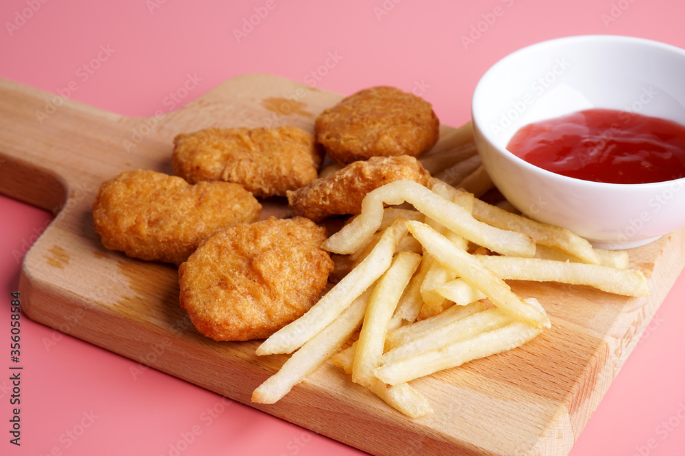 Naklejka premium Nugget, french fries plating on wood chopping board 