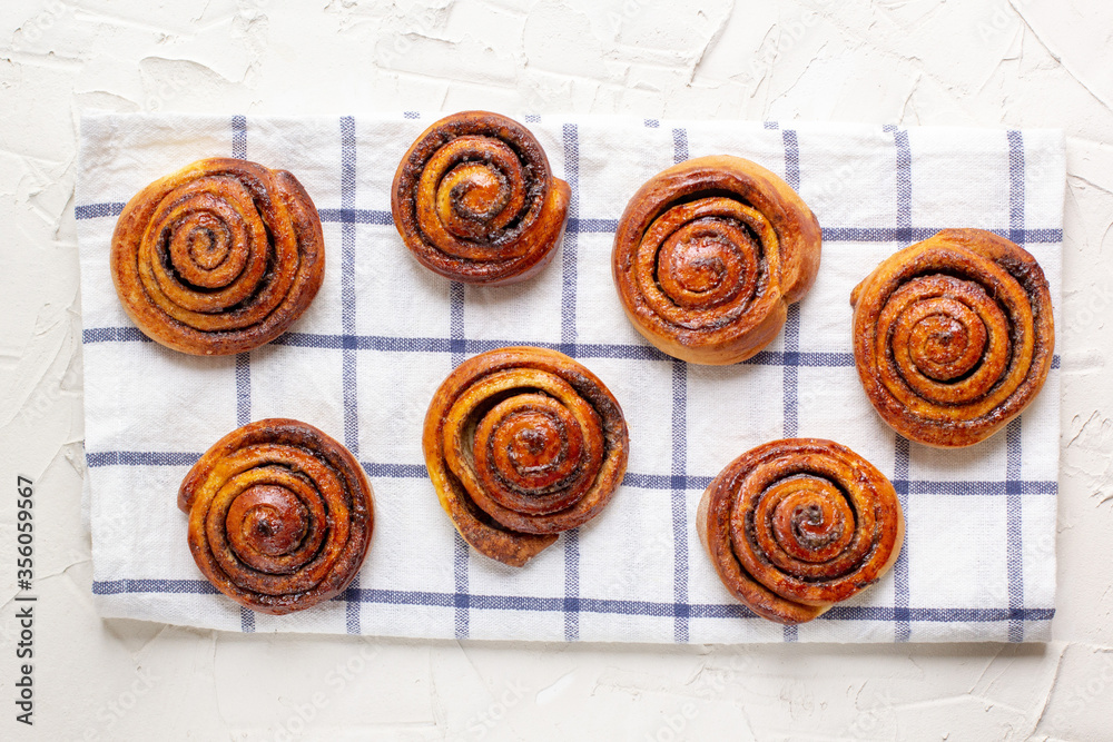 baked cinnamon buns on light background with checkered napkin baked cinnamon buns on light background with checkered napkin