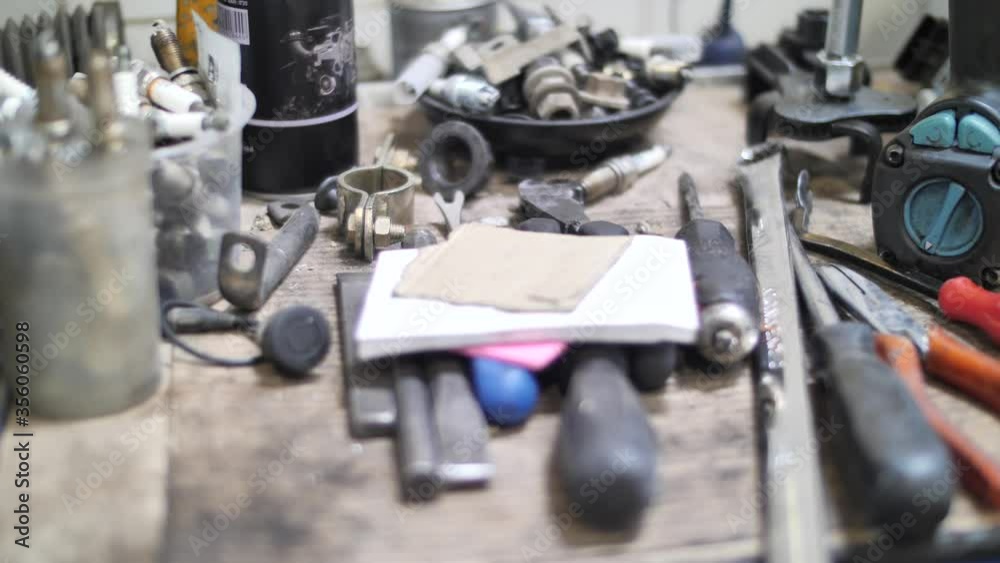 Craftsman tools and spare parts on workshop table in mechanic garage, close up Craftsman tools and spare parts on workshop table in mechanic garage, close up