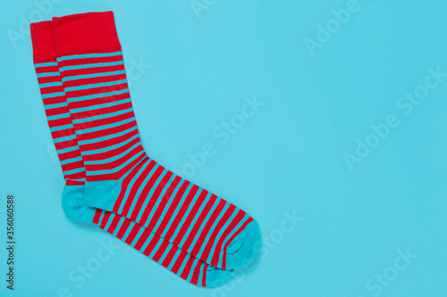 pair of socks in red and turquoise stripes, on a turquoise background, concept