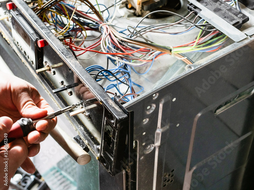 Foto repairman fixes panel of old electric stove during repair in home kitchen
