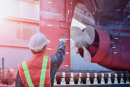 Shipyard ship repair worker with Talkie hand holding for shafting port controller, surveyor, inspecting the final repairing of propeller on dry dock. Detail of Propeller at dry dock in shipyard.