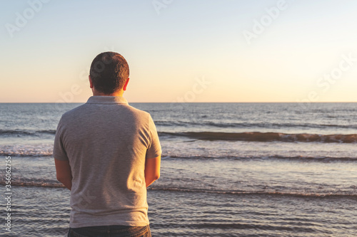 Young man meets the sunset on the beach at the sea