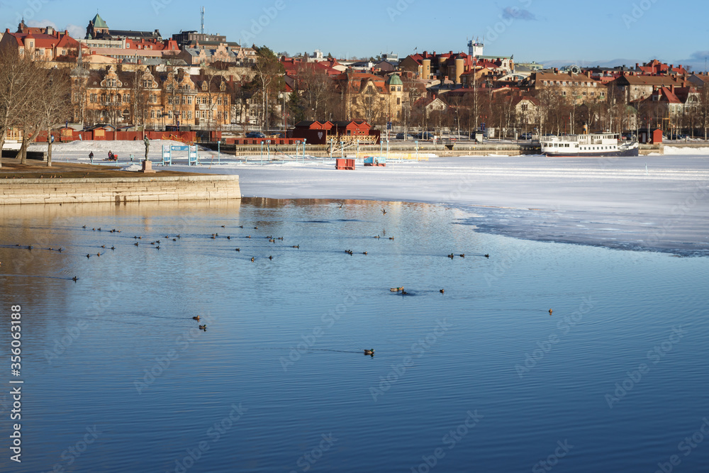 Melting ice on the shore of the lake on the background of Östersund