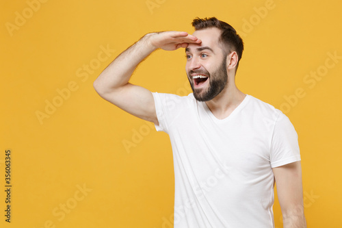 Bild auf Leinwand Excited young bearded man guy in white casual t-shirt posing isolated on yellow background in studio