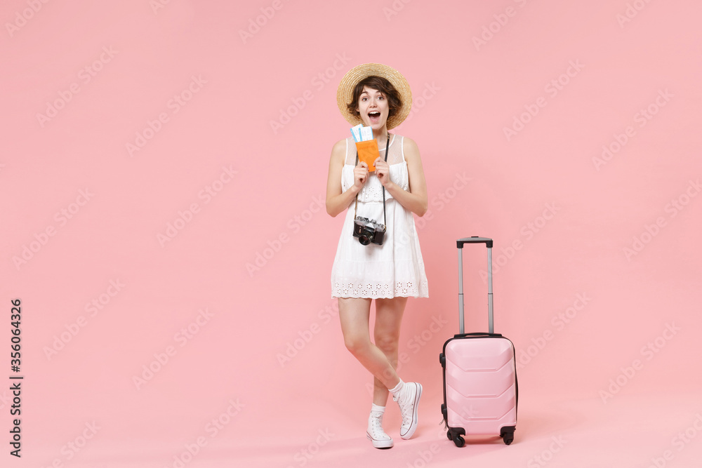 Excited tourist girl in dress hat with suitcase photo camera isolated on pink background. Traveling abroad to travel weekends getaway. Air flight journey concept. Hold passport tickets boarding pass. Excited tourist girl in dress hat with suitcase photo camera isolated on pink background. Traveling abroad to travel weekends getaway. Air flight journey concept. Hold passport tickets boarding pass.
