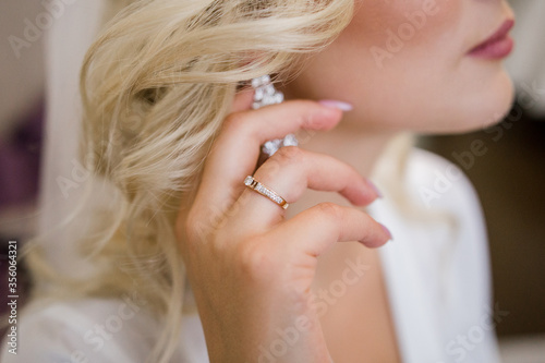 bride puts on beautiful earrings in her ear