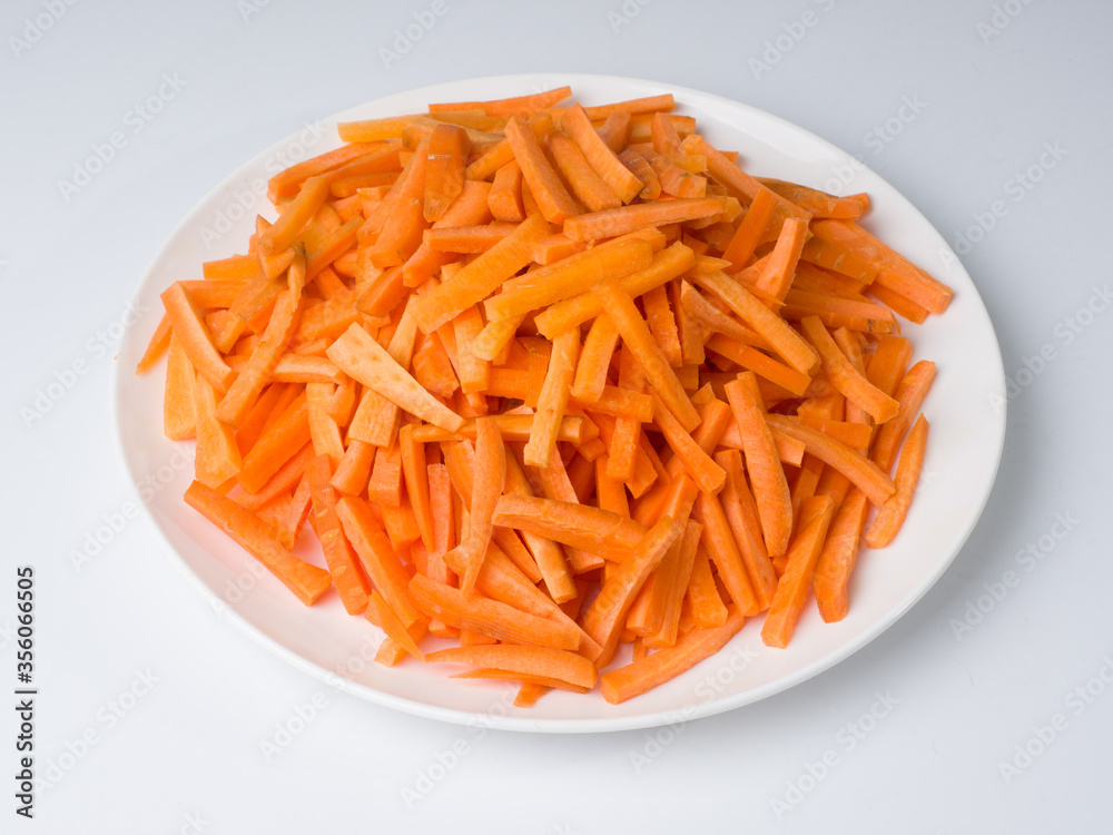 Sliced carrots on a white plate. Preparing an ingredient for a national Central Asian pilaf dish. Traditional cuisine Sliced carrots on a white plate. Preparing an ingredient for a national Central Asian pilaf dish. Traditional cuisine