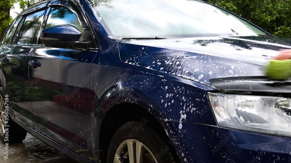 Man washing car with a sponge and foam in the house yard. Man washing car with a sponge and foam in the house yard.