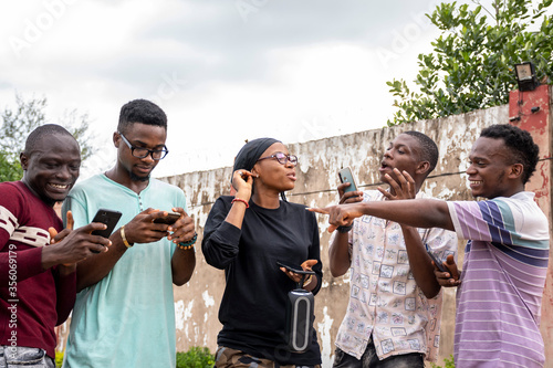 a group of young africans using their phones, hanging out together, students leisure on campus, conversation © Confidence