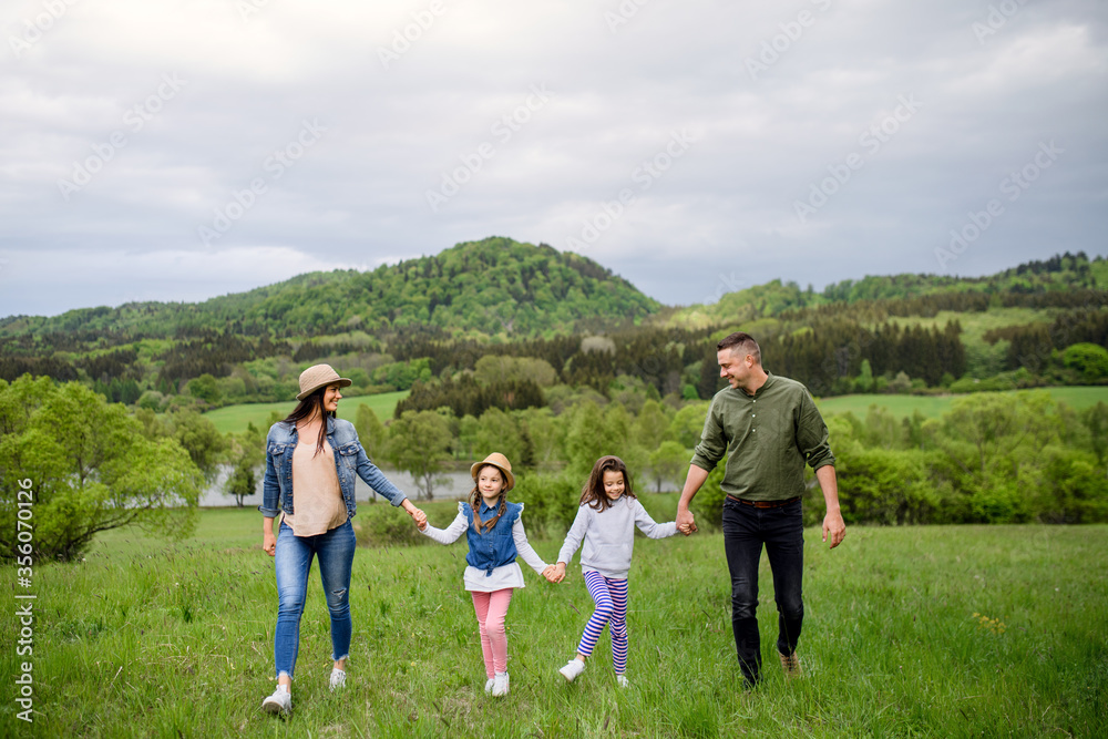 Fototapeta premium Happy family with two small daughters walking outdoors in spring nature.