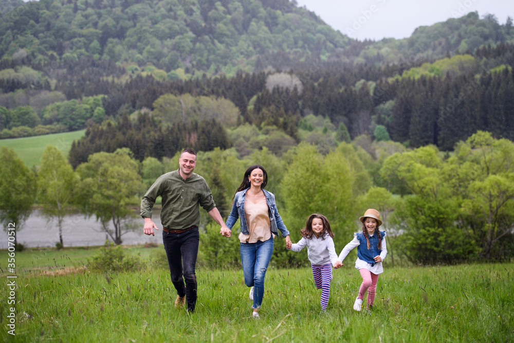 Obraz premium Happy family with two small daughters running outdoors in spring nature.