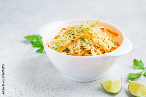 Fresh coleslaw salad with cabbage and carrots in white bowl.