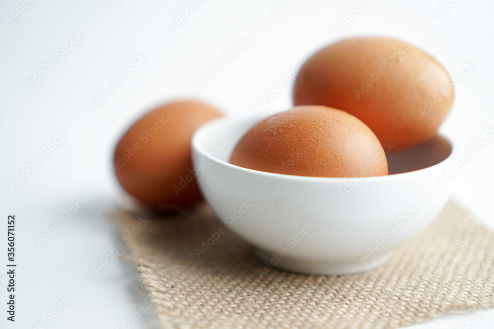 3 fresh poultry eggs on white bowl and brown fabric on white background.
3 fresh poultry eggs on white bowl and brown fabric on white background.