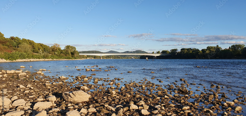 Bonn Beuel Germany mid September 2019 in the evening, you see the South Bridge with Siebengebirge sevenhills and banks of the Rhine on both sides with riverbed pebbles in the foreground Bonn Beuel Germany mid September 2019 in the evening, you see the South Bridge with Siebengebirge sevenhills and banks of the Rhine on both sides with riverbed pebbles in the foreground