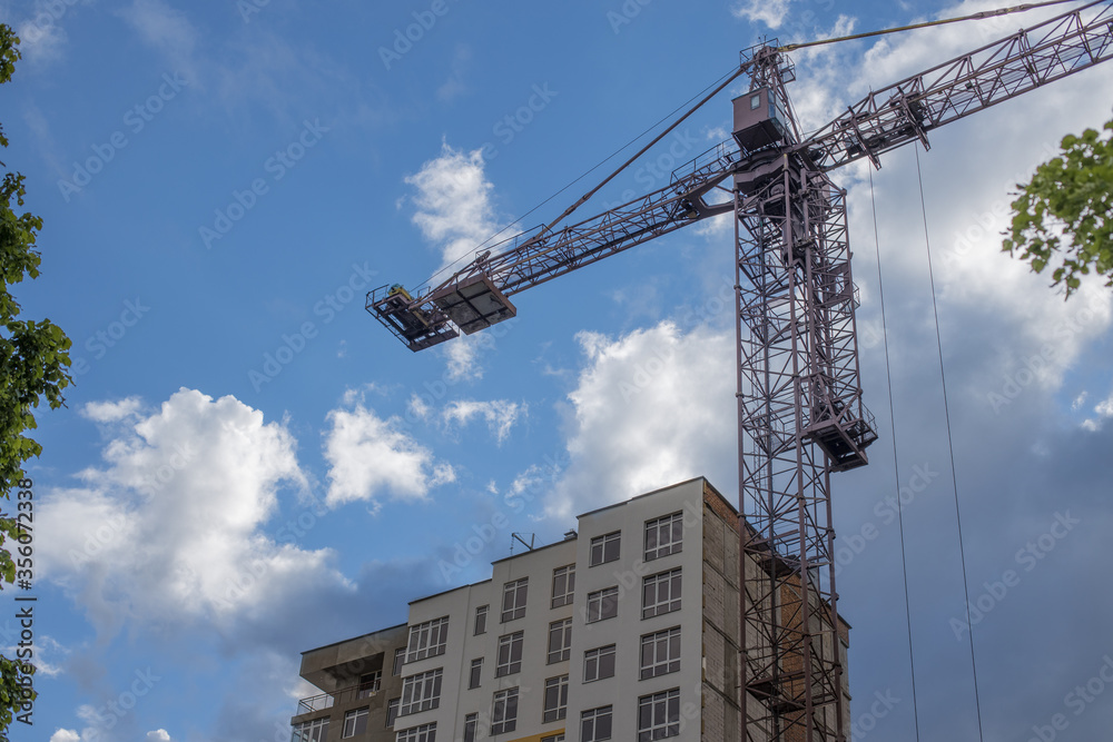 crane construction building process industrial urban view from below with blue cloudy sky