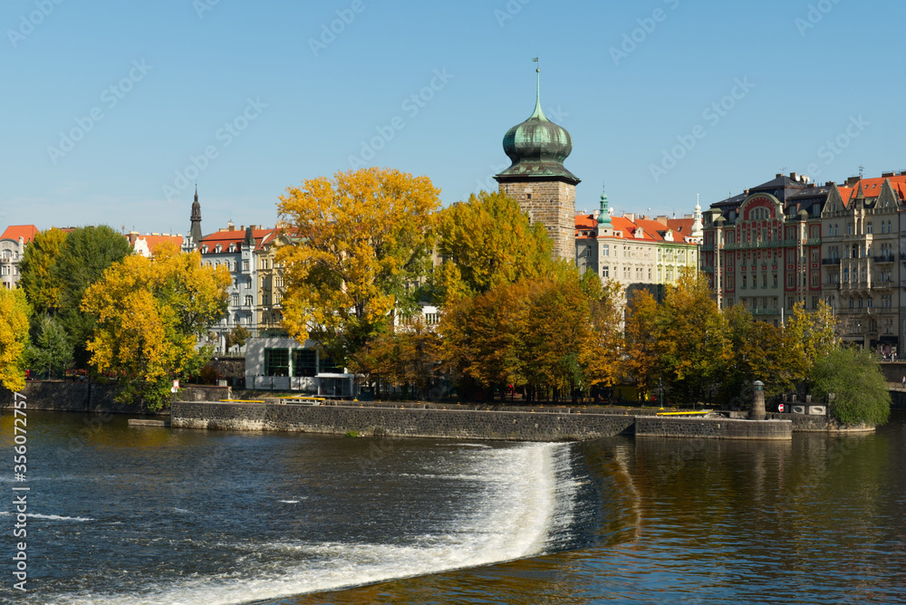 Ancient tower on the river bank in the fall. Autumn Prague. Landscape.