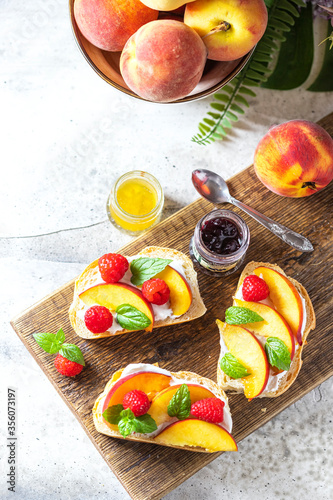 Summer snack - sandwiches with cream cheese and fresh peaches on a light concrete background. Homemade Summer Breakfast.