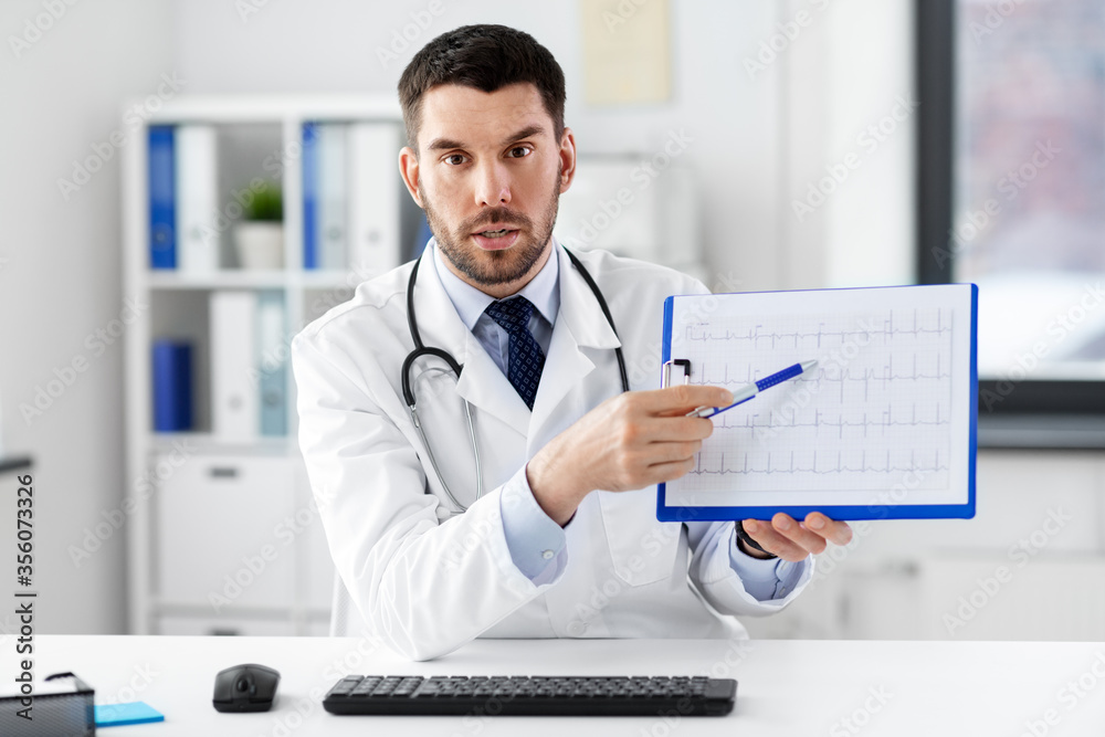 healthcare, medicine and people concept - male doctor with cardiogram on clipboard having video conference at hospital healthcare, medicine and people concept - male doctor with cardiogram on clipboard having video conference at hospital