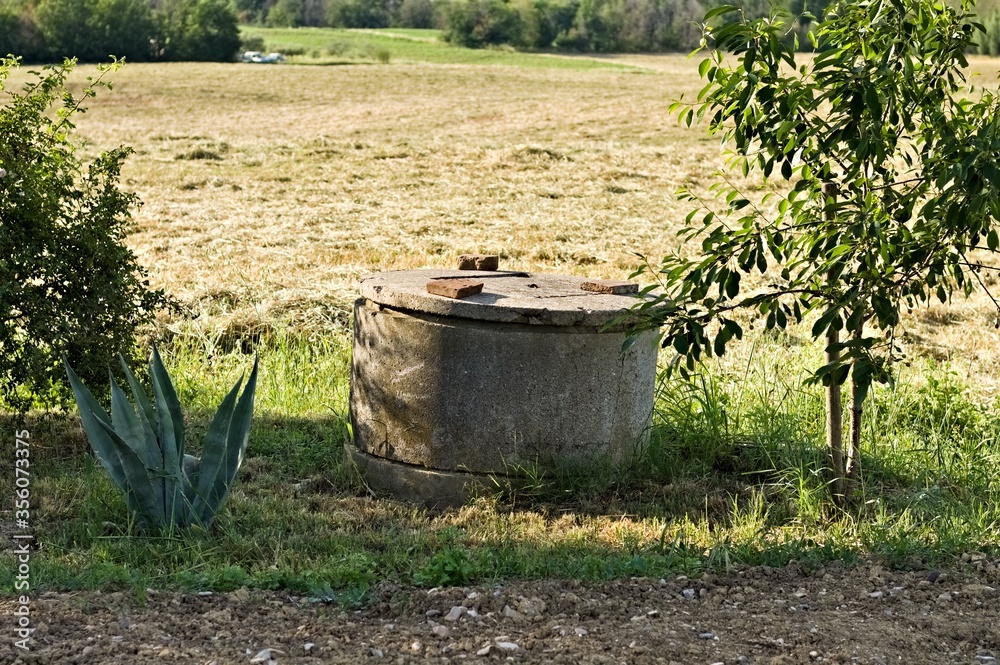 Concrete well closed with cover in the countryside (Pesaro, Italy, Europe) Concrete well closed with cover in the countryside (Pesaro, Italy, Europe)